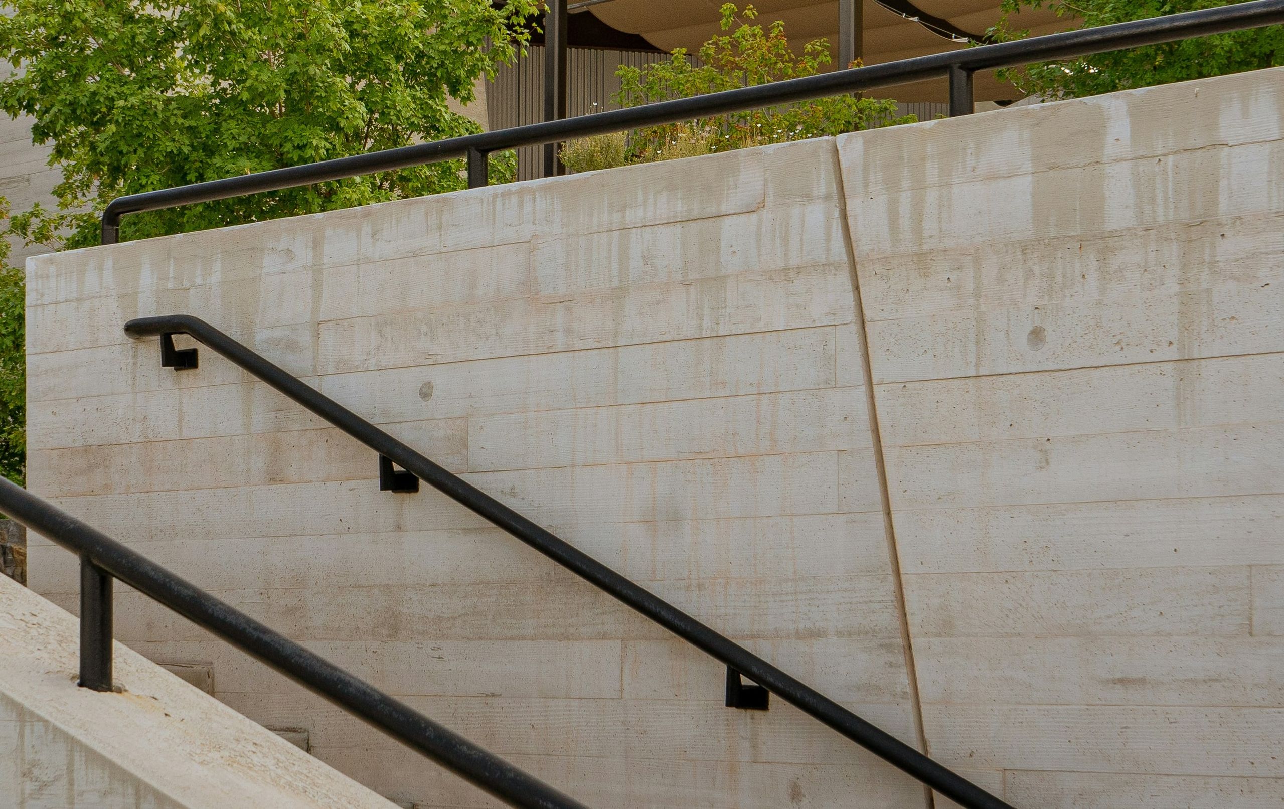 Board-formed concrete wall with a black steel handrail